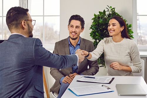 Man and woman shaking hands with a lawyer, preparing for an initial consultation with a Personal Injury Attorney in New York.
